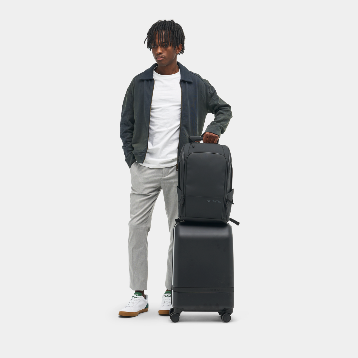 Person holding a black suitcase and backpack on a white background