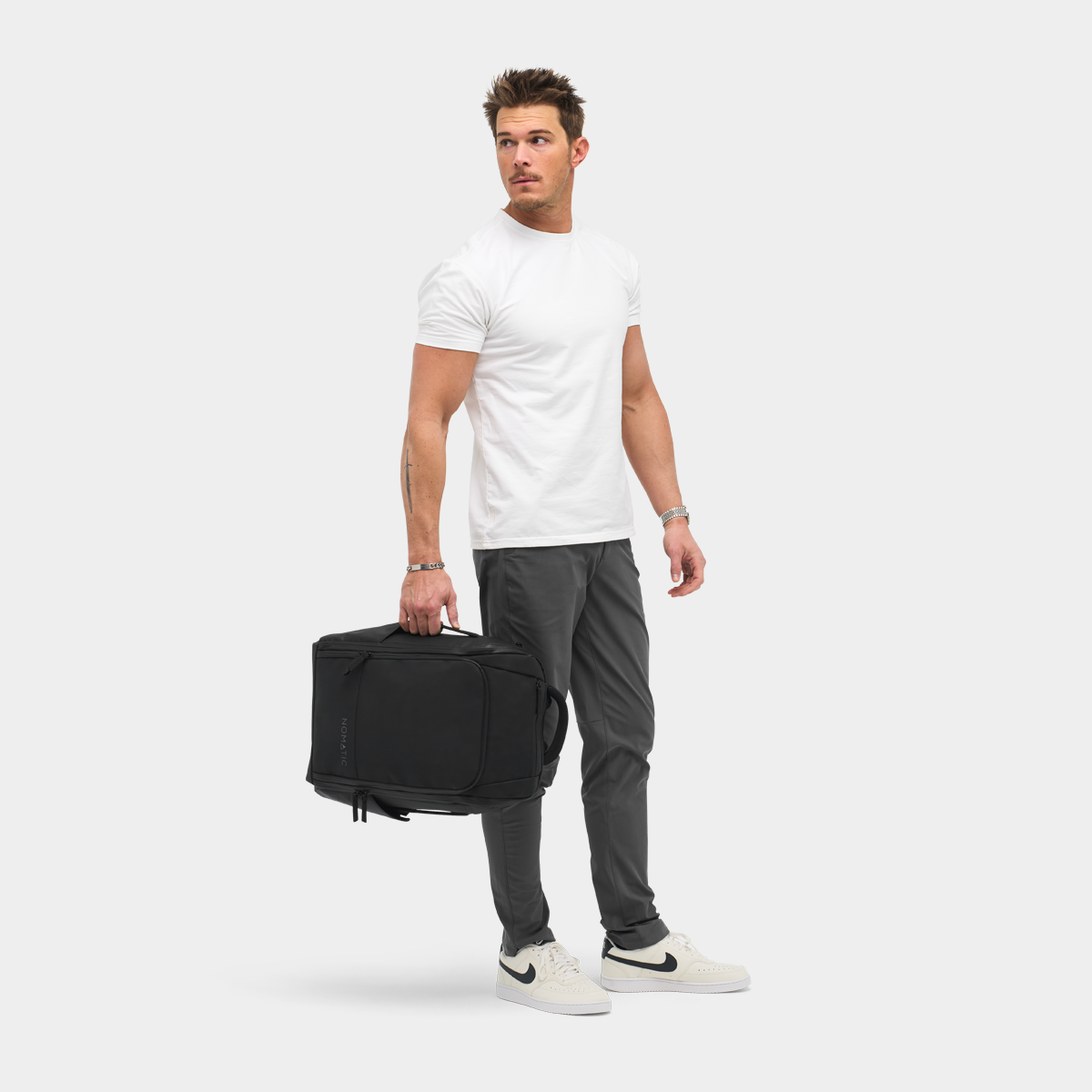 Nomatic Travel Pack on model showing convertible briefcase carry mode
